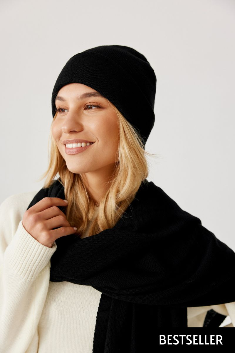 Czapka beanie czarna z wełny merino – stylizacja damska na modelce. Widok z boku uśmiechniętej dziewczyny.
