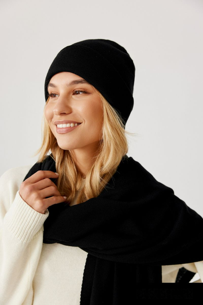 Czapka beanie czarna z wełny merino – stylizacja damska na modelce. Widok z boku uśmiechniętej dziewczyny.