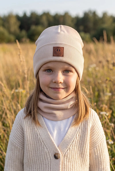 Dziecko w komplecie czapka i komin SMILE, kolor beżowy – widok z przodu.