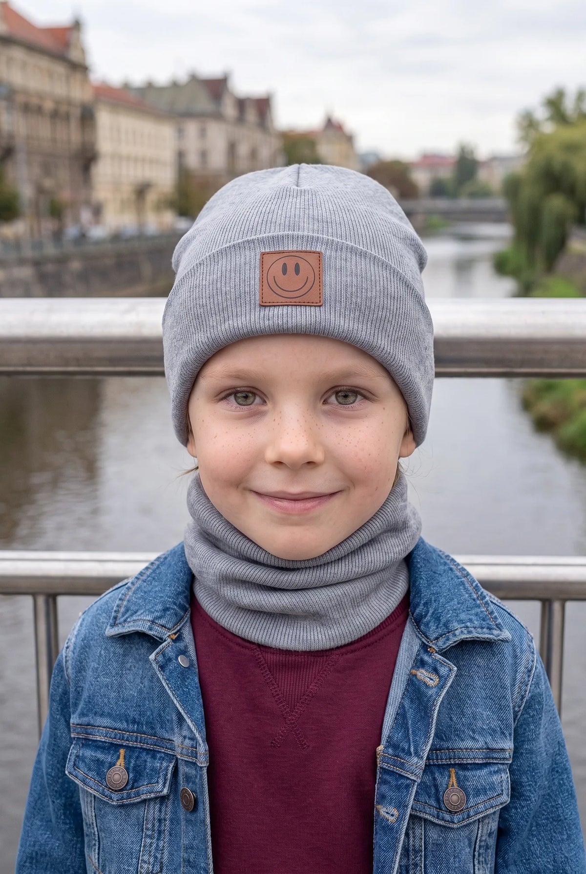 Dziecko w komplecie czapka i komin SMILE, kolor szary – widok z przodu.