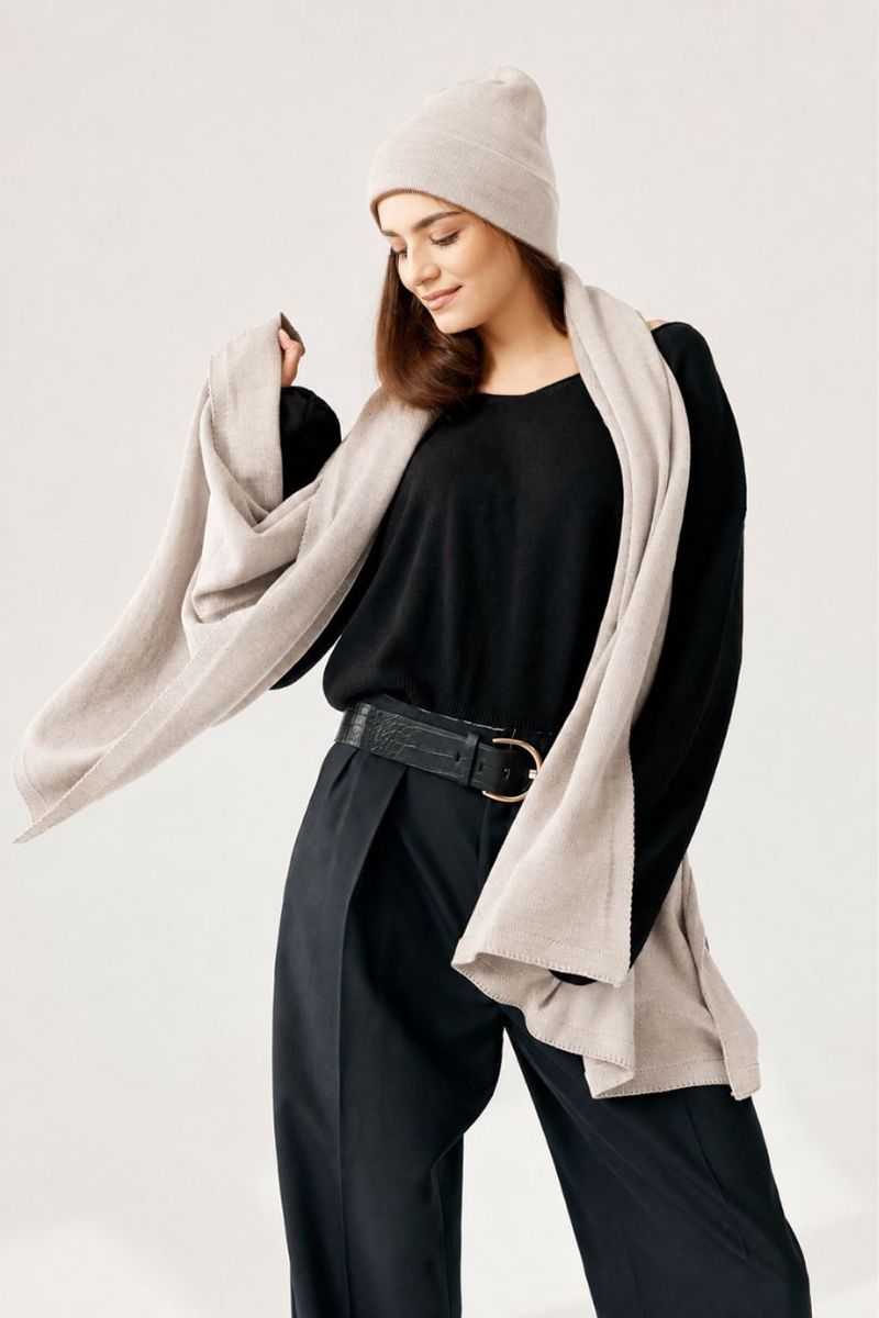 Beżowa czapka i szal z czystej wełny merino na modelce w eleganckiej czarnej stylizacji.
Modelka prezentująca jasnobeżową czapkę i szal wykonane w 100% z naturalnej wełny merino.